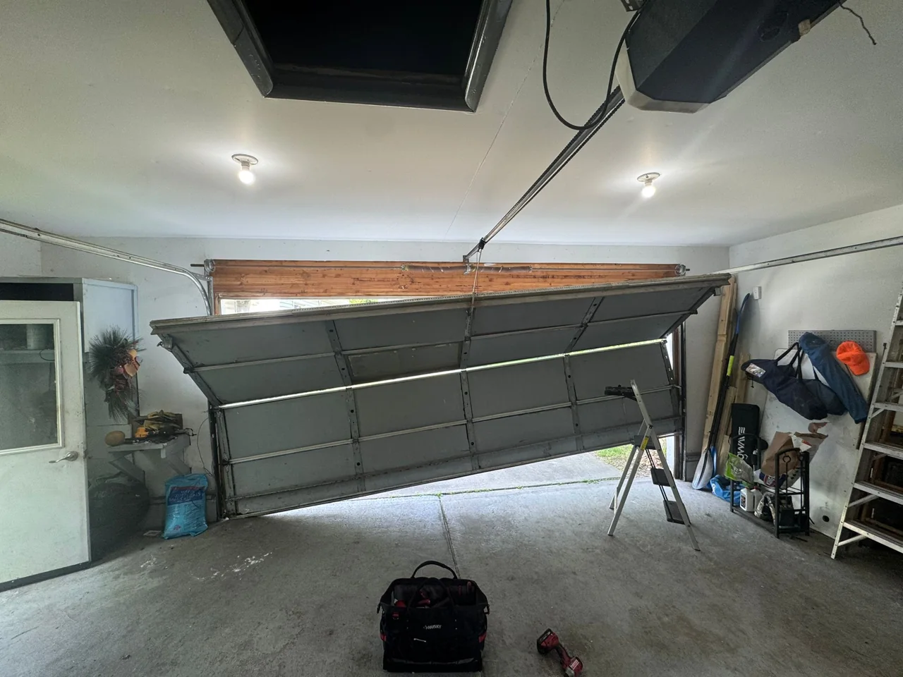 Crooked sectional garage door suspended unevenly inside a garage