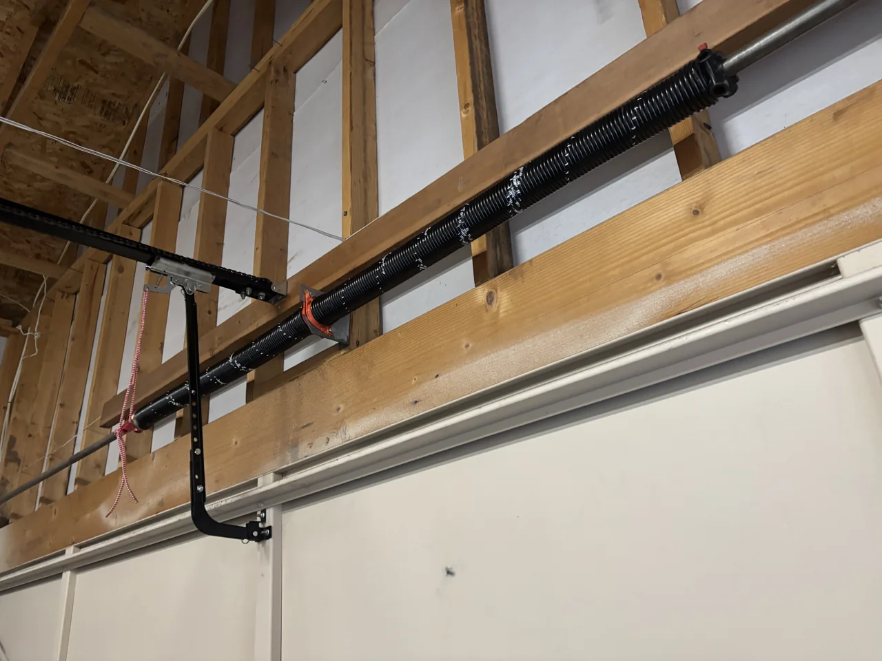 Torsion spring assembly above a sectional door in an unfinished garage